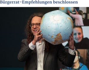 Screenshot: Mann mit Globus (Ball). Im Hintergrund Bilder von Videokonferenzen
