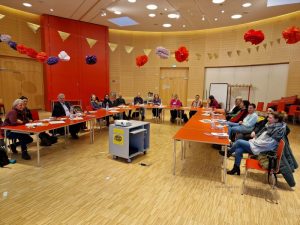 Foto von der Stadtteilkonferenz Höhenberg mit den Teilnehmerinnen und Teilnehmern an Tischen sitzend.